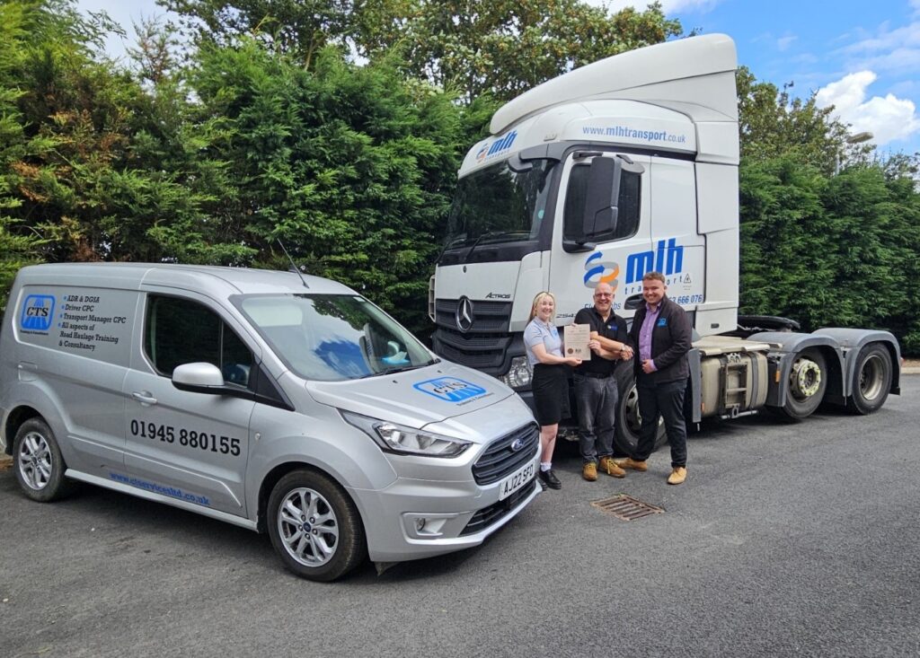 Matilda and Tom from CTS hand Nigel from MLH his Transport Manager CPC certificate, surrounded by vehicles from CTS and MLH.