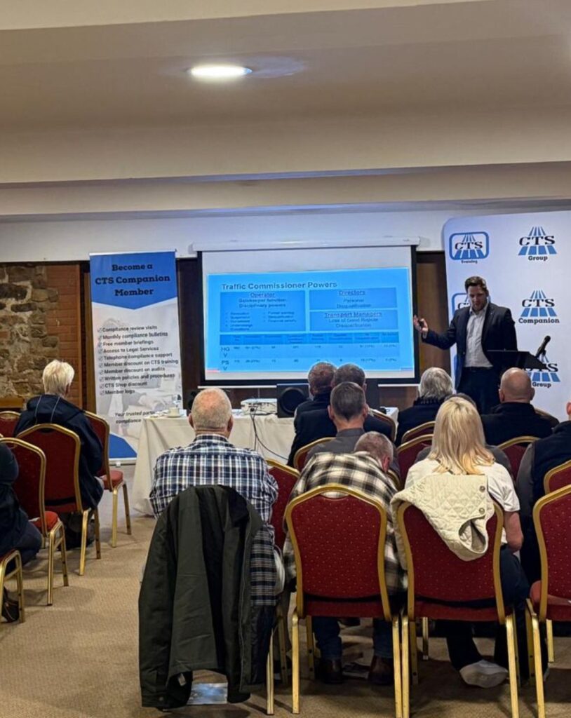 Shows Scott Bell from JMW Solicitors stood at the front of the room delivering a presentation on transport compliance to a group of attendees seated in front of him