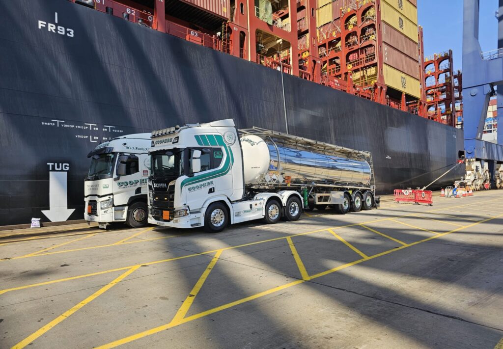 2 Coopers Transport lorries in front of a cargo vessel